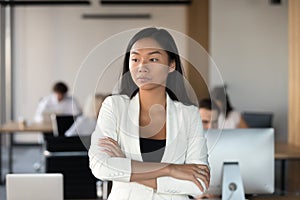 Serious asian female employee standing in coworking office and t