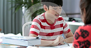 Serious Asian mother with son doing homework in the living room.