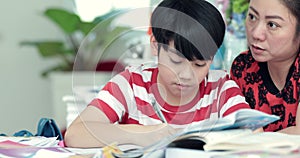 Serious Asian mother with son doing homework in the living room.