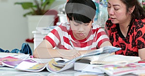 Serious Asian mother with son doing homework in the living room.