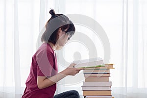 Serious Asian teen girl with eyeglasses pay attention reading book for examination or competition, university student read book at