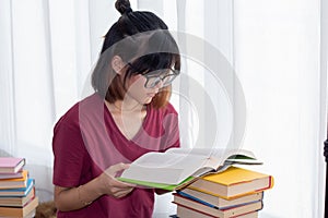 Serious Asian teen girl with eyeglasses pay attention reading book for examination or competition, university student read book at