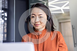 Serious Asian woman listening online conversation close up, businesswoman with headset phone, online customer support
