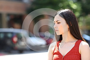 Serious asian woman looking away in the street