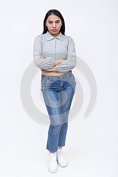 A serious asian woman with mid-length straight hair in a long sleeved cutoff blouse and blue jeans. Possible college student.