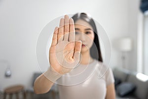 Serious Asian woman showing hand stop gesture, symbol of forbidding