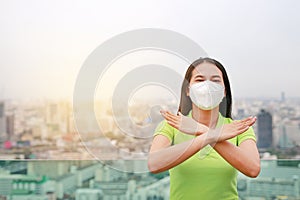 Serious Asian woman wearing a protection mask with making X sign with her arms to stop PM 2.5 air pollution in Bangkok city.