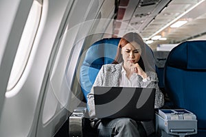 serious asian young woman using laptop sitting near windows at first class on airplane during flight, Traveling and