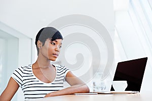 Serious attractive african businesswoman working with laptop and drinking coffee