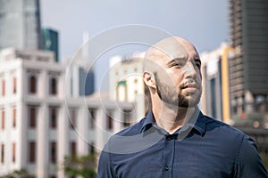 Serious attractive man standing against a cityscape and thinking