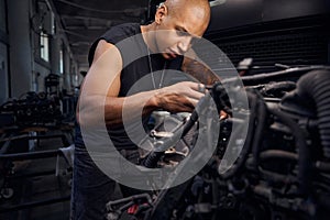 Serious auto-mechanic going through carburetor, checking serviceability