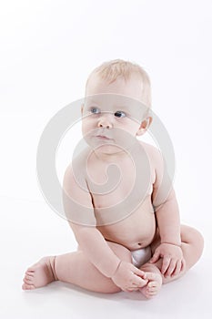Serious baby-boy in a diaper sitting on the floor
