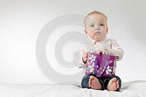 Serious baby boy holding some present in his arms. Thoughtful infant kid with a gift. Copy space. Ready postcard