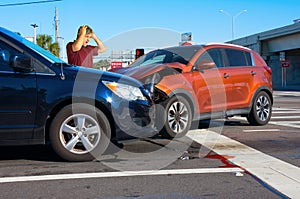 Serious bad car wreck at intersection with very upset man driver looking at damage