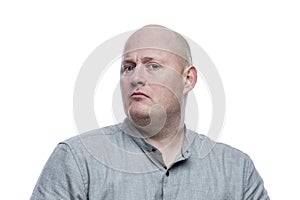 Serious bald man in a gray shirt. Isolated on a white background. Close-up