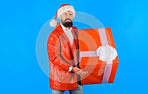Serious bearded delivery man with big Christmas gift. Delivery service. Businessman in Santa hat with present box. Merry