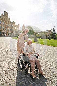 Serious bearded male person pushing the wheelchair