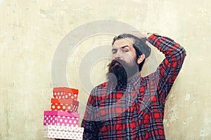 Serious bearded man holding colorful gift boxes stacked in hands