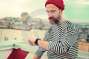 Serious bearded man looking at his watch while waiting for the girlfriend