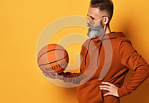 Serious bearded man in sunglasses, hoodie holding basket ball