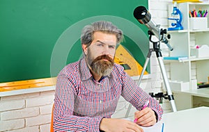 Serious bearded teacher or student in classroom. Learning, education, school concept. Male teacher preparing lessons in