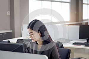 Serious beautiful Asian woman officer typing desktop computer while sitting at office desk. Concentrate female worker working at