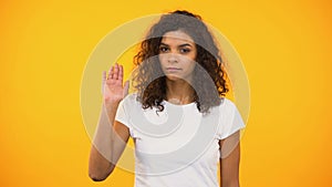 Serious biracial woman showing no gesture to camera against yellow background