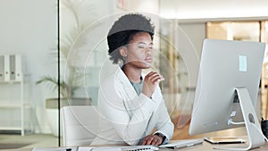 A serious black business woman looking focused while working on computer in a modern office. Confident young