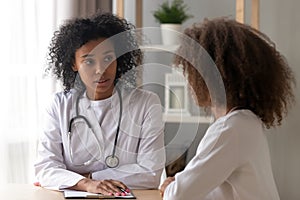 Serious black female doctor consult teenage girl