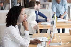 Serious black female employee thinking sitting in front of computer