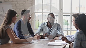 Serious black male boss explain strategy at multiracial group meeting