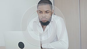 Serious black man working use computer looking in monitor screen at office. African american businessman worling at