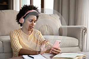Serious Black student girl wearing headphones, watching learning webinar