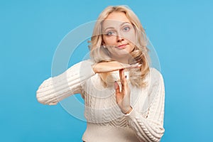 Serious blond woman in knitted sweater showing time out gesture, need more time for work , deadline, asking for pause