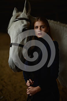 Serious blonde in blue jacket stands with a horse.