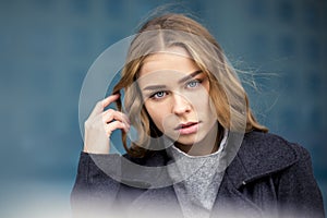 Serious blonde with long hair in the city walks