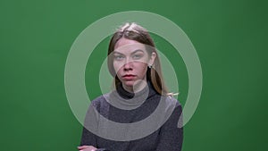 Serious blonde model watching into camera with contempt isolated on green chromakey background.