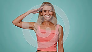 Serious blonde woman giving salute listening to order as if soldier, following discipline, obeying