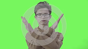 Serious boy in eyeglasses making no gesture at green background. Portrait of confident Caucasian teenager disagree with