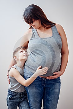 Serious boy holding belly of pregnant mother