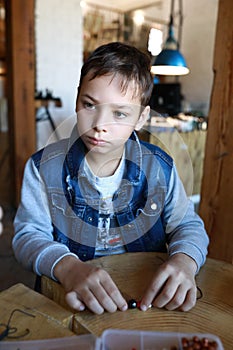 Serious boy making bracelet at workshop