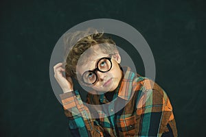 Serious boy, primary school student on a dark background