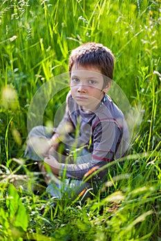 Serious boy sitting in grass