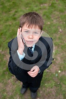 Serious boy in suit speaking over the mobile
