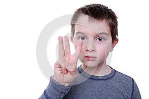 Serious boy with three fingers up