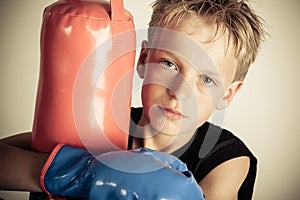 Serious boy wearing black shirt hugs punching bag