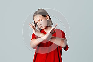 Serious brunette teen girl shows cross stop gesture, looking unamused, saying no, forbid something, standing over grey background