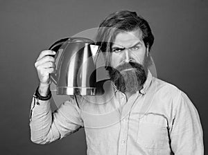 serious brutal man with moustache and beard. electric home device. bearded man use red electric kettle. male
