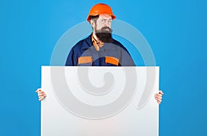 Serious builder man in protective helmet and clothing with advertising banner. Construction Worker in hard hat shows