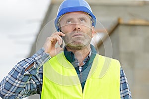 serious builder men in white helmet on phone